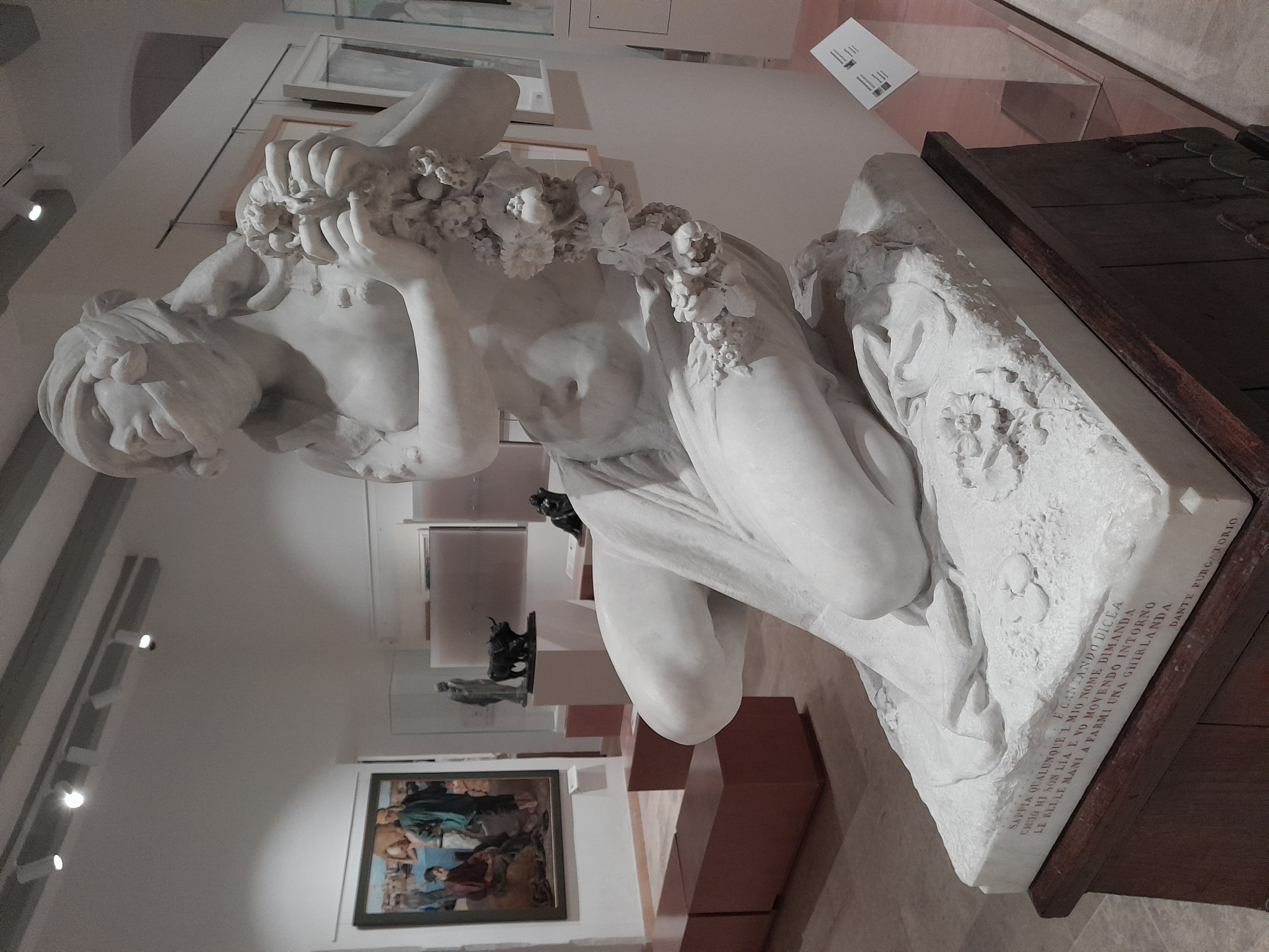 Vista lateral da escultura de Lia por Eugenio Maccagnani, figura bíblica representada em mármore com guirlanda de flores.